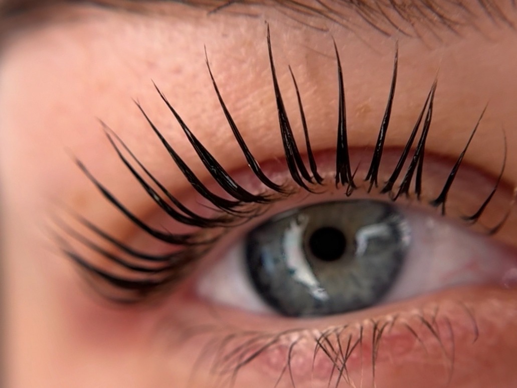 Lash lift: gekrulde, geverfde wimpers boven een blauw oog